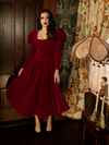 A hauntingly elegant Haunted Beauty Victorian Dress in Crimson, showcasing delicate floral lace accents, a buttoned front bodice, and a long, flowing skirt for an effortlessly romantic look.