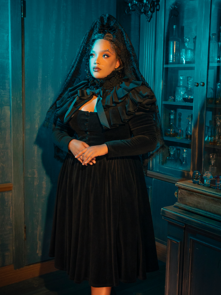 The Haunted Beauty Victorian Mourning Dress with Capelet in Black wraps you in the velvet night. Its capelet, like the wings of a raven, whispers tales of love lost and the solemn beauty found in grief. This ensemble is a tribute to the art of mourning, a wearable elegy that speaks to the soul.