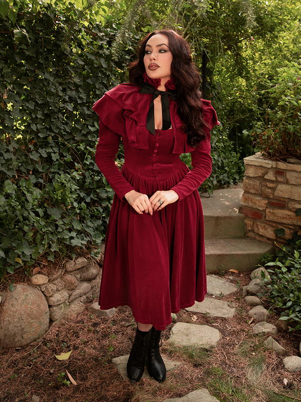 Micheline Pitt commands attention in the Haunted Beauty Capelet in Crimson, its sculpted collar and silken weight evoking vintage grandeur and gothic grace.