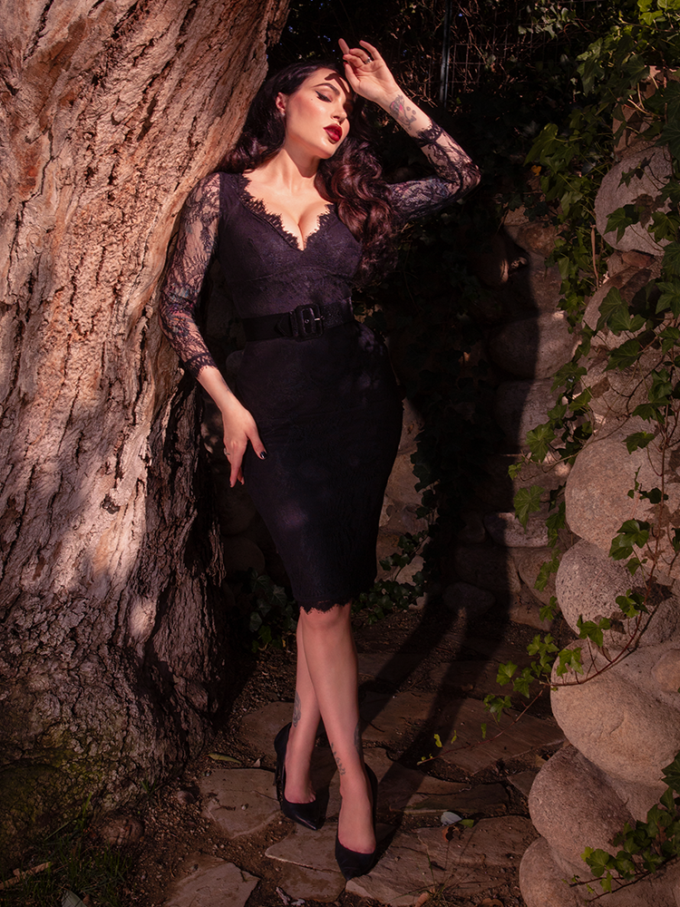A captivating vision of dark luxury, a female model styles a rich black lace dress that epitomizes midnight romance and the striking, sophisticated artistry of high-end gothic apparel.
