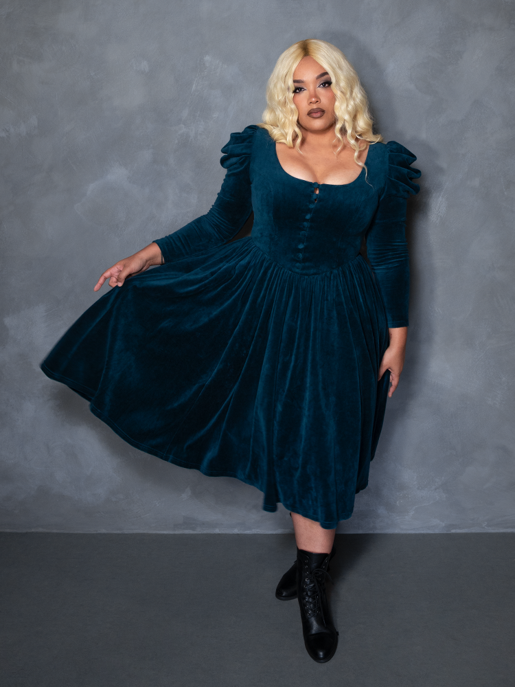 Female model wearing the CRIMSON PEAK™ Lady Lucille Victorian Dress with Capelet in Teal, showcasing high-fashion gothic glamour and shadowy grace.