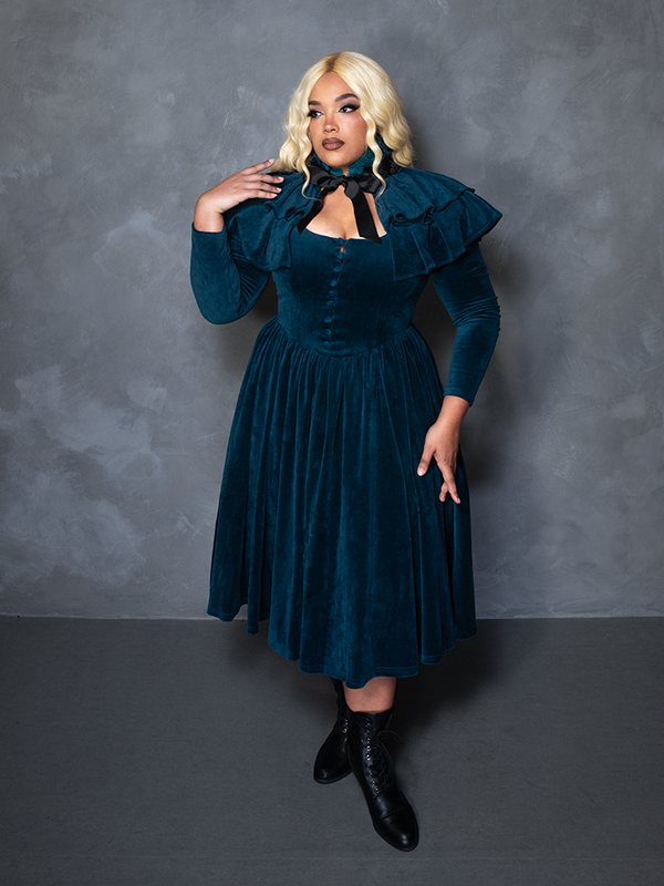 Model styled in the CRIMSON PEAK™ Lady Lucille Victorian Dress with Capelet in Teal, personifying dark academia clothing and cinematic drama.