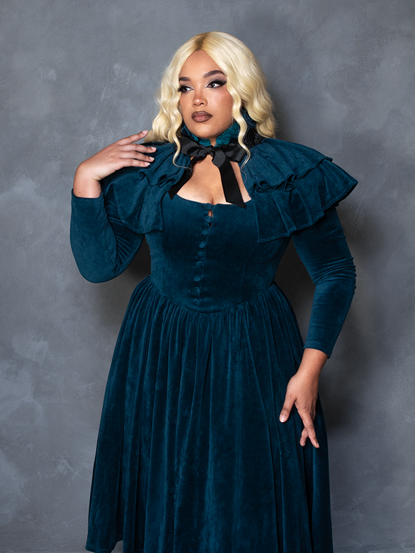 Female model wearing the CRIMSON PEAK™ Lady Lucille Victorian Dress with Capelet in Teal, embodying dark elegance and romantic goth fashion.