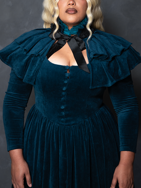 Model styled in the teal CRIMSON PEAK™ Lady Lucille Victorian Dress with Capelet, capturing vintage gothic dress allure and atmospheric charm.