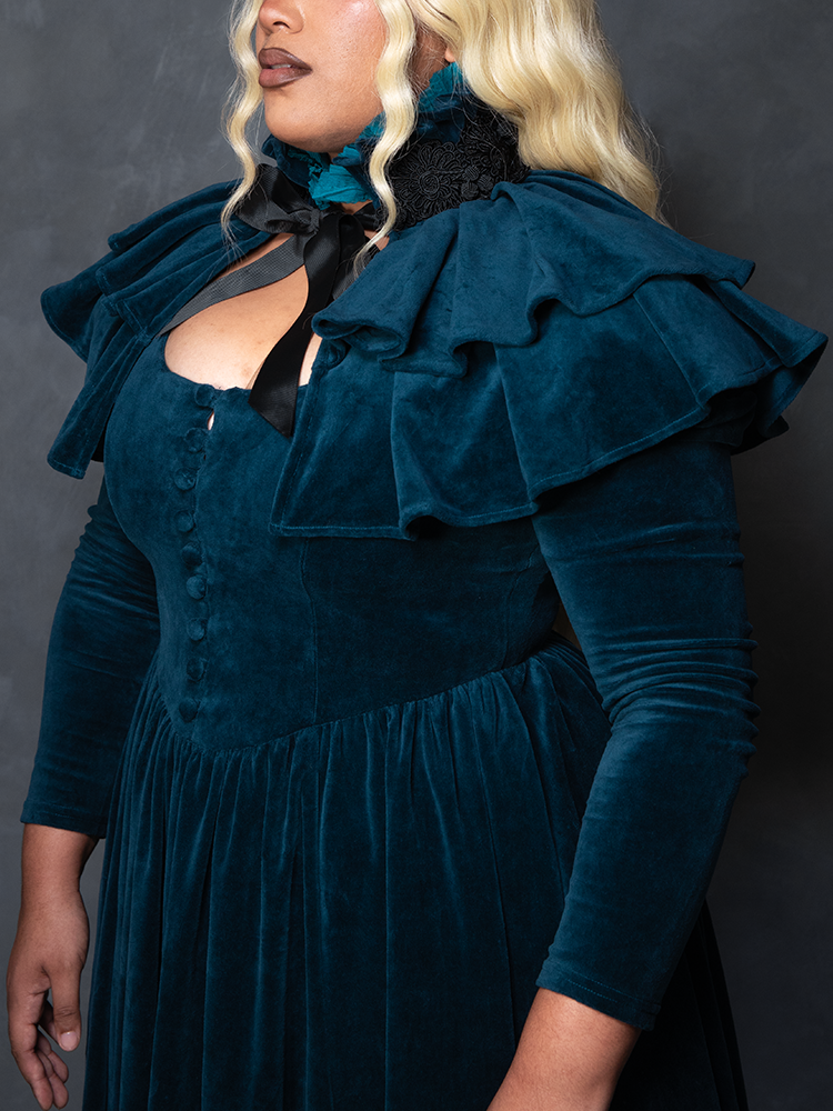 Model styled in the CRIMSON PEAK™ Lady Lucille Victorian Dress with Capelet in Teal, manifesting dark couture design and haunting allure.