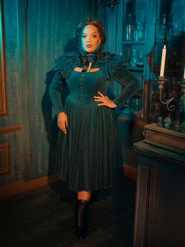 Sophisticated and hauntingly beautiful, the CRIMSON PEAK™ Lady Lucille Dress in Teal combines gothic elegance with Victorian charm, featuring a high collar, lace overlays, and a capelet for added drama.