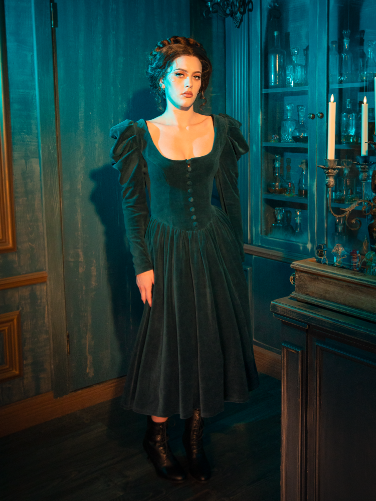 With a fitted bodice and flowing skirt, the CRIMSON PEAK™ Lady Lucille Victorian Dress in Teal embraces vintage Victorian elegance, with lace detailing and a capelet that adds timeless drama and sophistication.