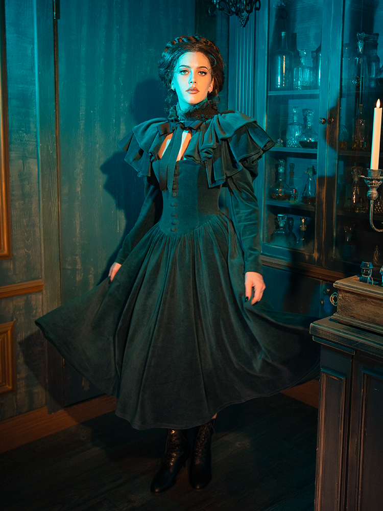 Inspired by Victorian style, the CRIMSON PEAK™ Lady Lucille Dress in Teal features luxurious teal fabric, a high neckline, and delicate lace accents, finished with a dramatic capelet for a truly captivating look.