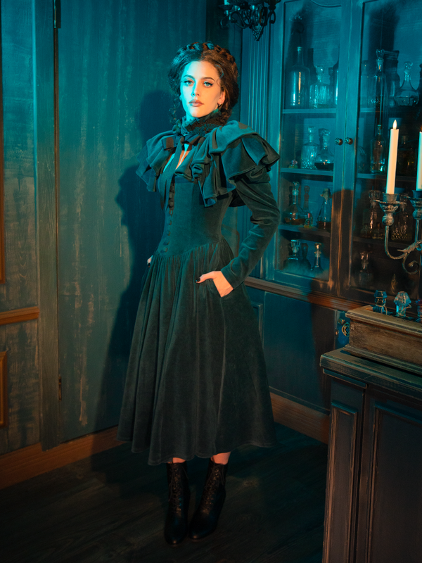 The CRIMSON PEAK™ Lady Lucille Victorian Dress with Capelet in Teal is the ideal statement piece for any gothic-inspired wardrobe, blending Victorian fashion with a captivating, timeless elegance.