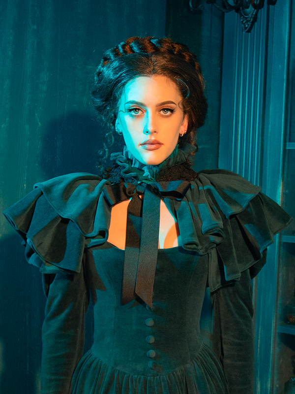 Embrace gothic romance in the CRIMSON PEAK™ Lady Lucille Victorian Dress with Capelet in Teal, designed with a high collar, vintage lace details, and an elegant capelet for a dramatic, refined silhouette.