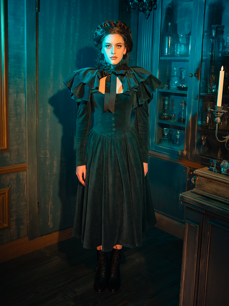 With its intricate lace detailing and ethereal capelet, the CRIMSON PEAK™ Lady Lucille Victorian Dress in Teal is the perfect blend of romantic gothic elegance and vintage allure.