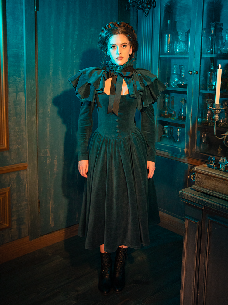 A truly captivating dress, the CRIMSON PEAK™ Lady Lucille Victorian Dress in Teal offers a high-neck design, intricate lace details, and a flowing capelet that adds an air of mystery and dark elegance.