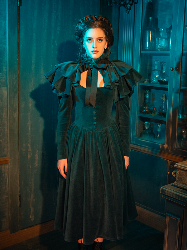 Step into the haunting elegance of the CRIMSON PEAK™ Lady Lucille Victorian Dress in Teal, featuring a high-neck design, intricate lace detailing, and a dramatic capelet, perfect for channeling old-world charm with a gothic twist.