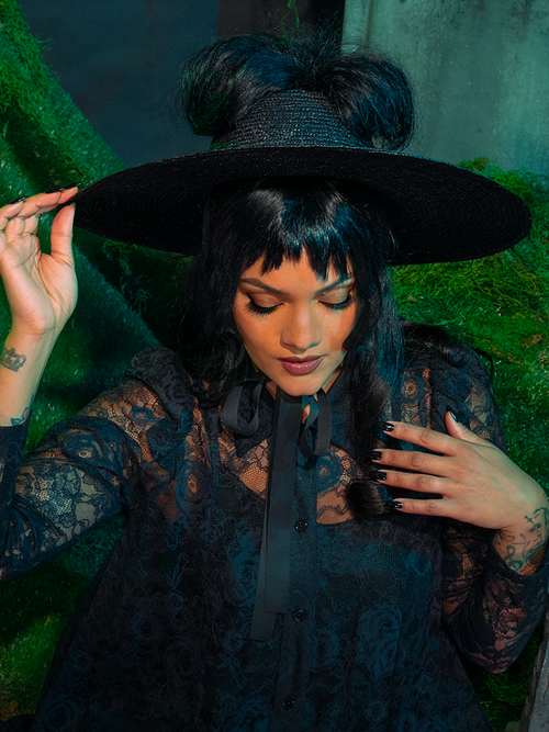 The Beetlejuice™ Lydia Deetz Open Crown Hat is a hauntingly chic tribute to gothic icon Lydia Deetz. With its bold, open crown and dramatic brim, this statement piece adds eerie elegance to any outfit, conjuring the essence of dark, mysterious allure.