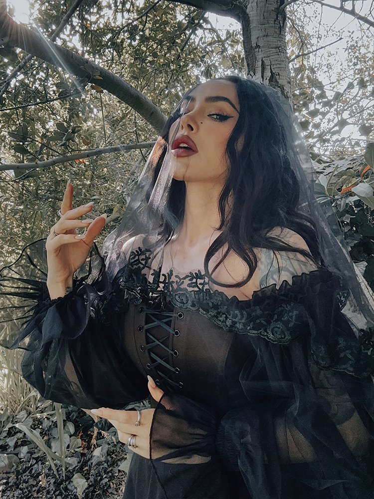 A romantic off-the-shoulder neckline adorned with delicate tulle ruffles, capturing the essence of dark romance and timeless feminine allure.