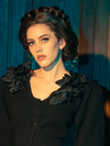 With an air of gothic elegance, female models strike various poses while showcasing the Victorian Mourning Knit Cardigan in Black.