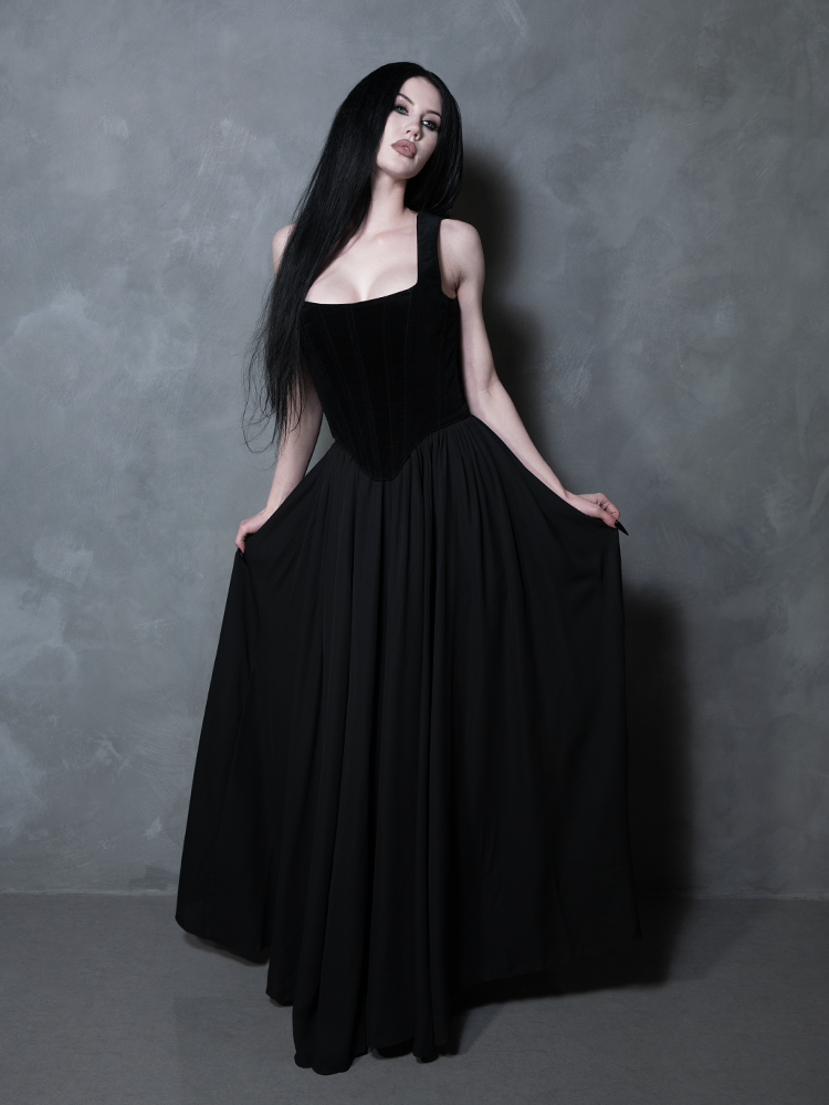 Exuding effortless poise, a female model highlights a sheer black maxi skirt that brings a touch of midnight enchantment and refined elegance to classic gothic styling.