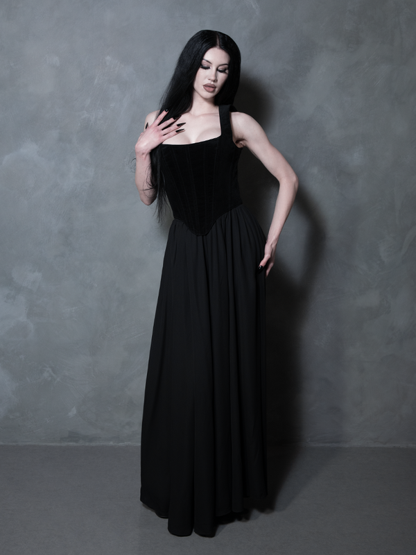 Redefining the boundaries of dark luxury, a female model showcases a fluid black maxi skirt that captures a spirit of elegant, high-end gothic romance.