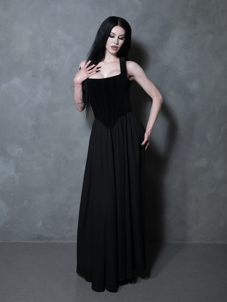 Redefining the boundaries of dark luxury, a female model showcases a fluid black maxi skirt that captures a spirit of elegant, high-end gothic romance.