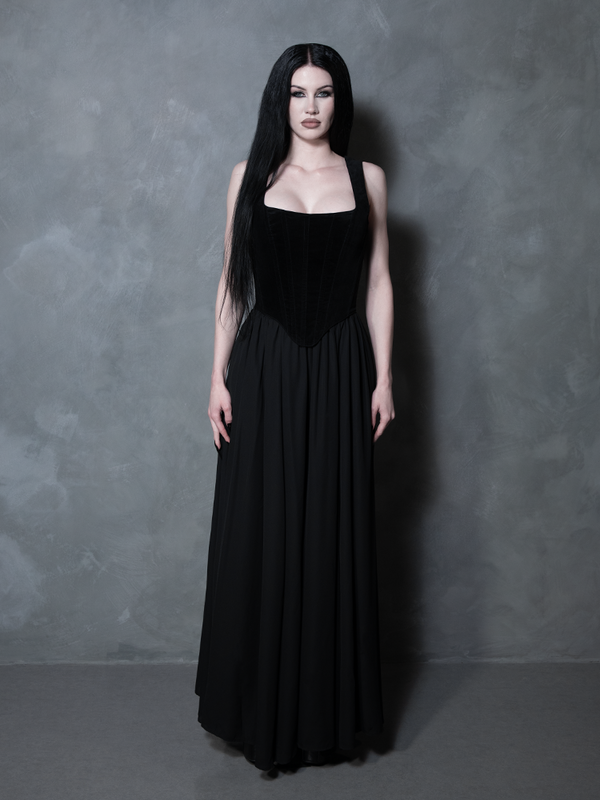A captivating vision of dark luxury, a female model styles a rich black flowing skirt that epitomizes midnight romance and the striking, sophisticated artistry of high-end gothic apparel.