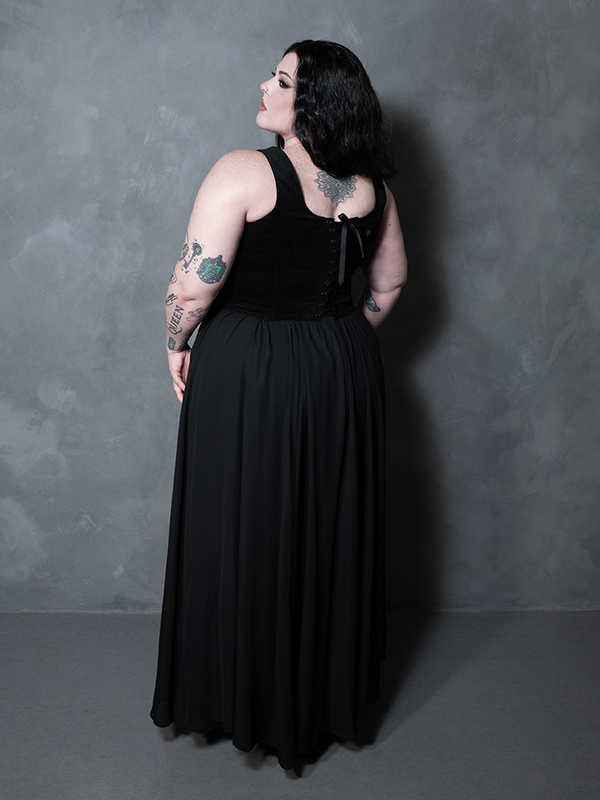 A masterclass in modern alternative drama, a female model exudes dark elegance in a cascading black floor-length skirt designed for high-fashion impact.