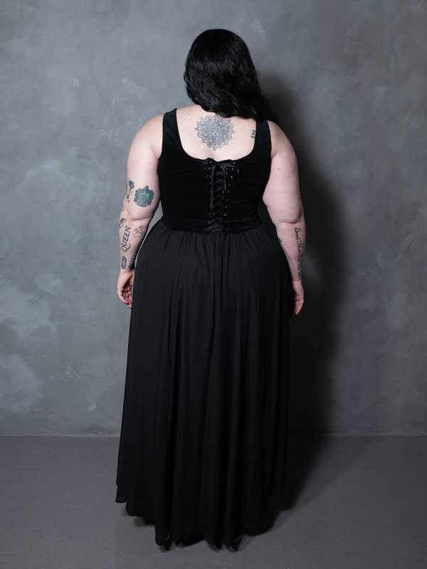 Embodying a look of pure, dark luxury, a female model commands the night in a fluid black chiffon maxi skirt that beautifully merges modern alternative style with classic gothic romance.