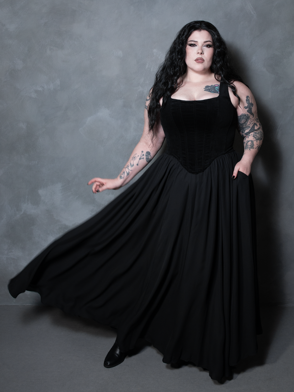 A masterclass in bold alternative style, a female model pairs a cascading black chiffon skirt with moody styling to redefine contemporary high-end gothic clothing.