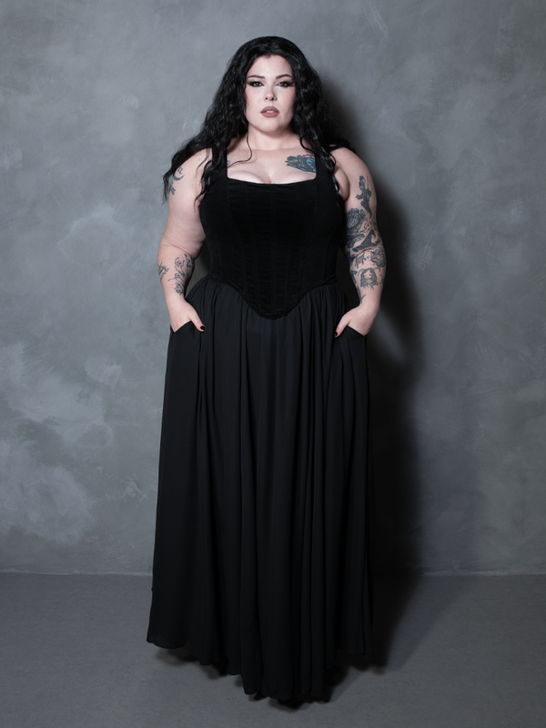 With a look steeped in moody elegance, a female model showcases a breathtaking black chiffon maxi skirt that seamlessly elevates luxury alternative wardrobes.