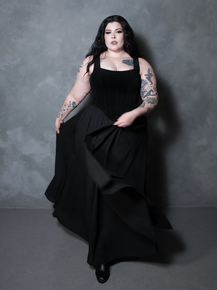 A breathtaking vision of luxury, a female model effortlessly blends classic alternative elements with a sweeping black chiffon maxi skirt for a truly spellbinding ensemble.