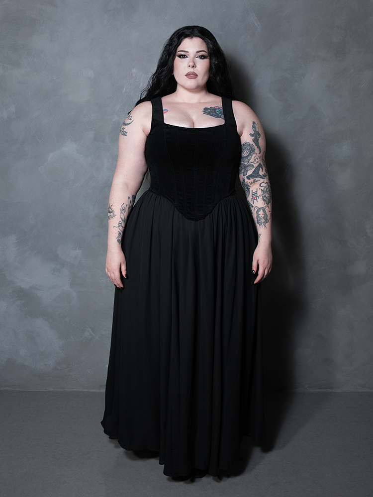 A beautiful expression of dark sophistication, a female model wears a flowing black chiffon skirt that encapsulates the dramatic artistry of premium alternative apparel.