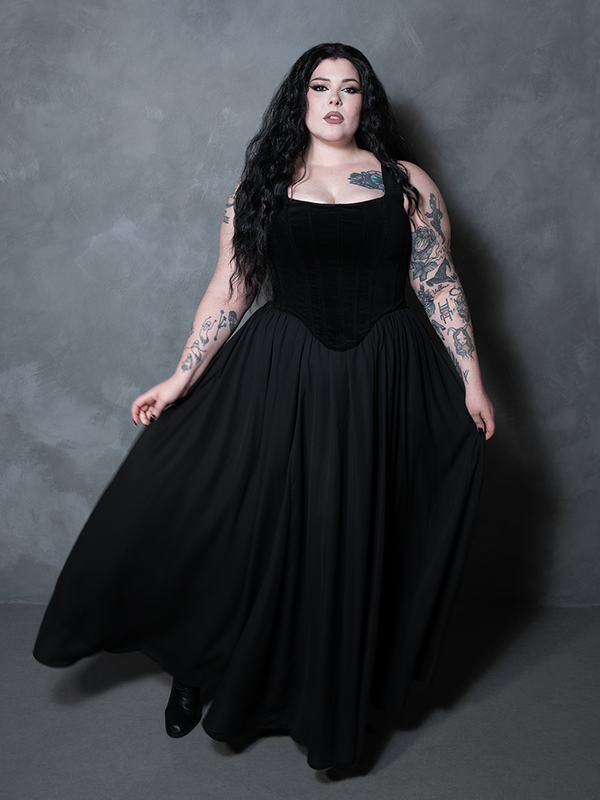 A captivating statement of high-fashion alternative couture, a female model wears a dark, romantic black chiffon skirt built for creating unforgettable silhouettes.