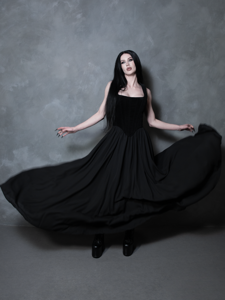 Radiating vintage-inspired charm and modern alternative sophistication, a female model wears a sweeping black gothic skirt that commands absolute presence in the shadows.