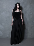 A model poses in a moody, dimly lit room wearing the Countess Black Velvet Corset, a centerpiece of high-end gothic glamour women's clothing.