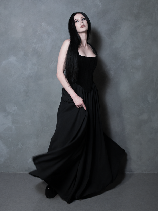 A classic piece of alternative fashion, a female model embodies a poetic, romantic aesthetic in an enchanting black chiffon floor-length skirt designed for high-fashion drama.