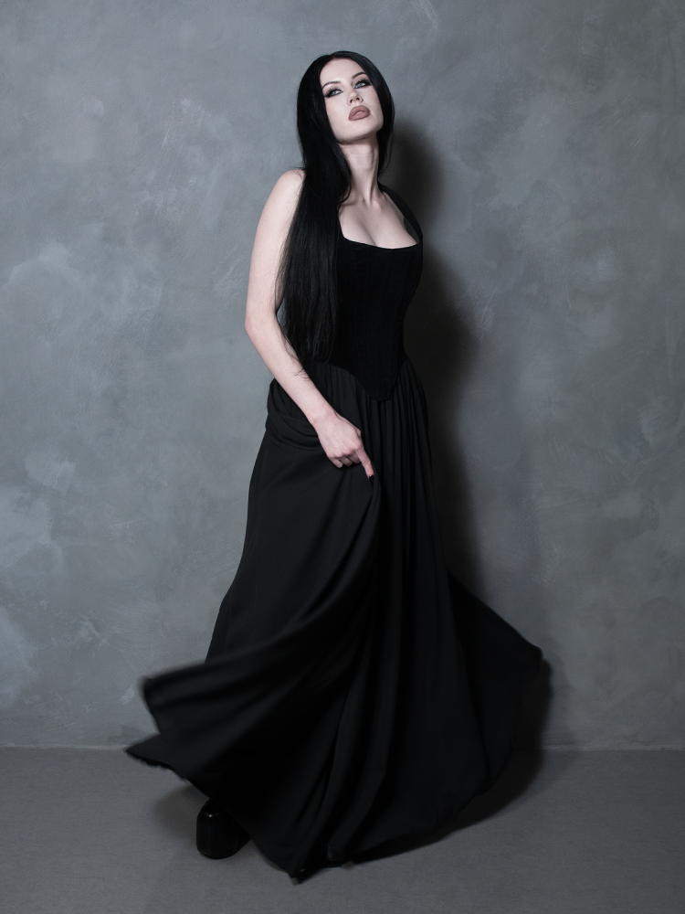 A classic piece of alternative fashion, a female model embodies a poetic, romantic aesthetic in an enchanting black chiffon floor-length skirt designed for high-fashion drama.