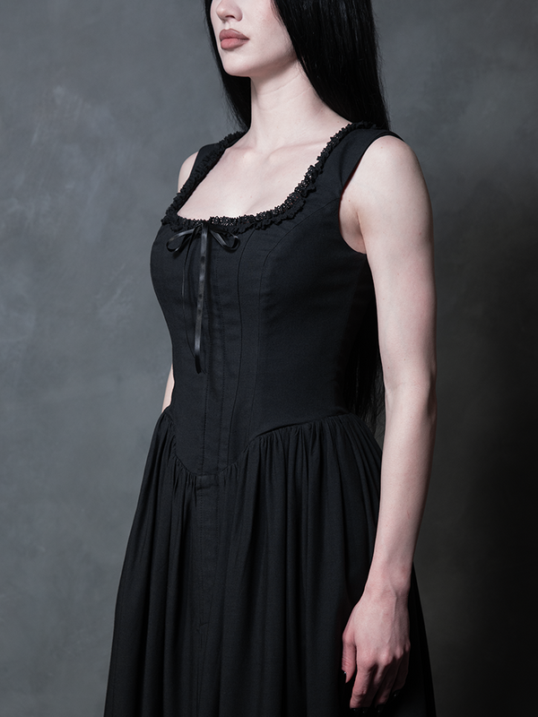 Dressed in the exquisite Nightshade Underpinning Dress in Antique Black, a female model commands the room with an undeniable aura of dark elegance.