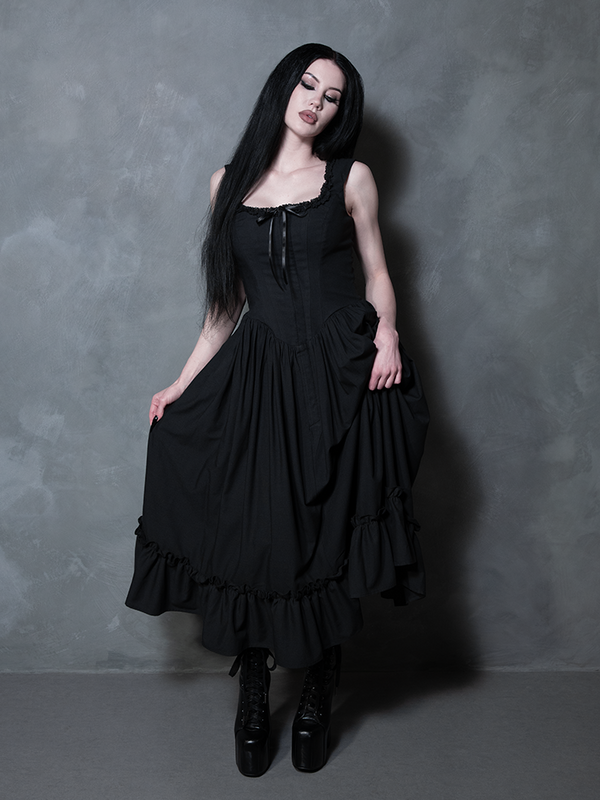 A female model embodies the ultimate vision of gothic glamour, draped in the hauntingly beautiful Nightshade Underpinning Dress in Antique Black.
