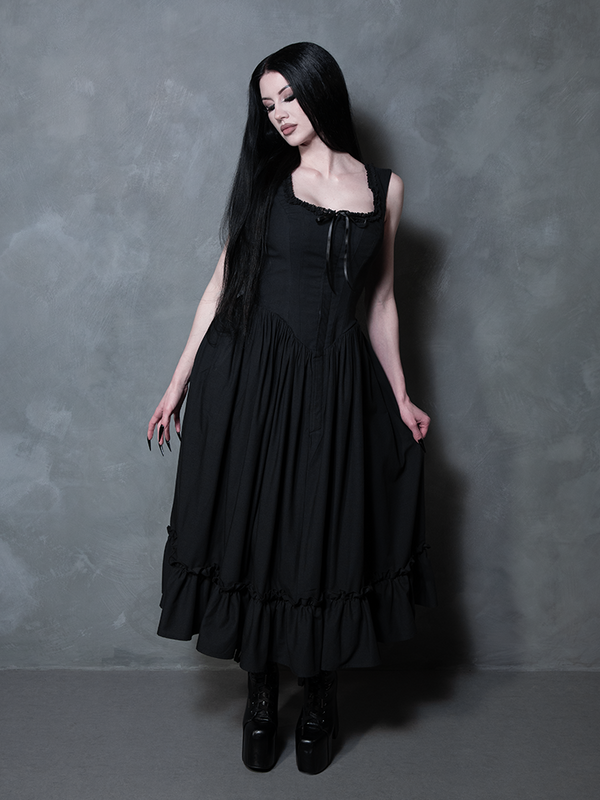 The essence of a gothic femme fatale is brought to life as a female model wears the seductive Nightshade Underpinning Dress in Antique Black.