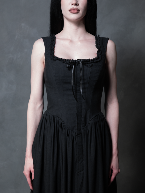 A female model captures the poetic mystery of high-fashion gothic style clothing while wearing the enchanting Nightshade Underpinning Dress in Antique Black.