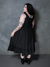 A female model masterfully showcases the dark elegance of alternative evening wear in the Nightshade Underpinning Dress in Antique Black.