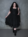 The epitome of dark luxury is achieved as a female model wears the exquisite Nightshade Underpinning Dress in Antique Black.