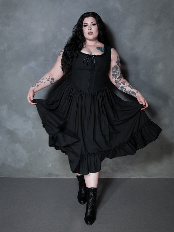 A female model evokes a sense of cinematic dark romance, draped elegantly in the Nightshade Underpinning Dress in Antique Black.