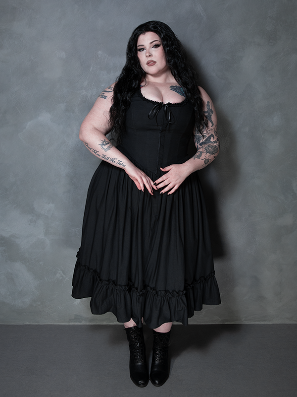 A female model channels a deep, brooding sophistication while styled in the magnificent Nightshade Underpinning Dress in Antique Black.
