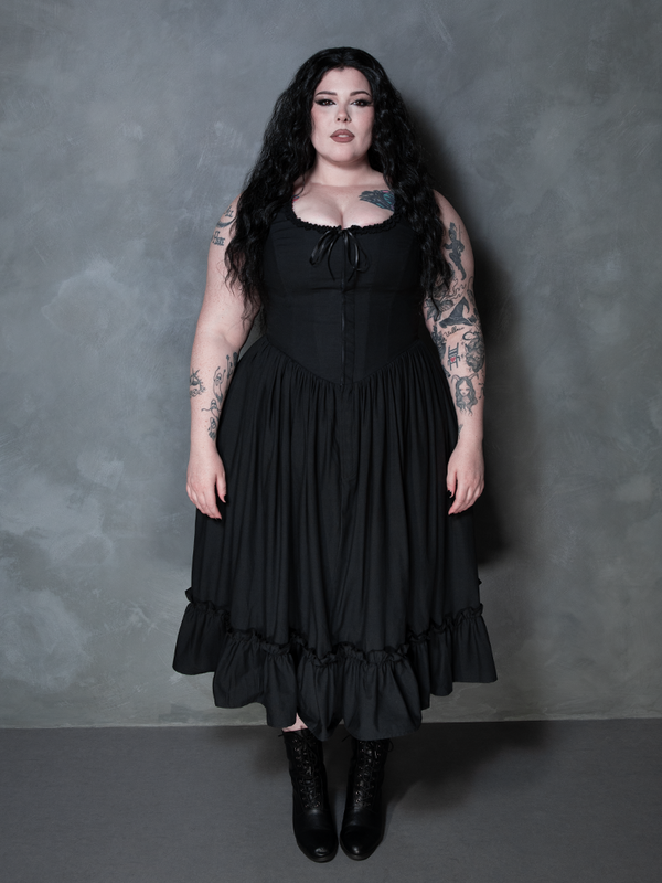 A female model channels an alluring, vampiric romance while styled in the decadent Nightshade Underpinning Dress in Antique Black.