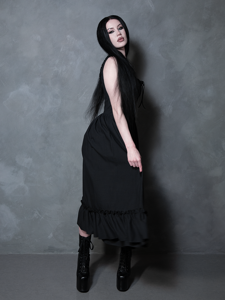 Evoking the spirit of a classic gothic novel protagonist, a female model wears the haunting Nightshade Underpinning Dress in Antique Black.