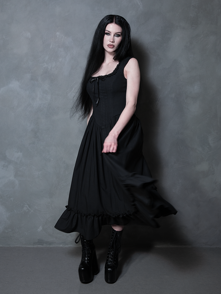 A female model captures a look of quiet, powerful intensity while adorned in the Nightshade Underpinning Dress in Antique Black.