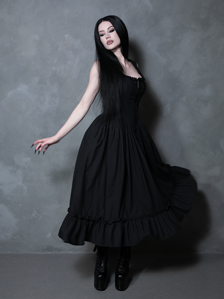 A female model transports us to a bygone era of dark opulence, styled beautifully in the Victorian Goth Nightshade Underpinning Dress in Antique Black.