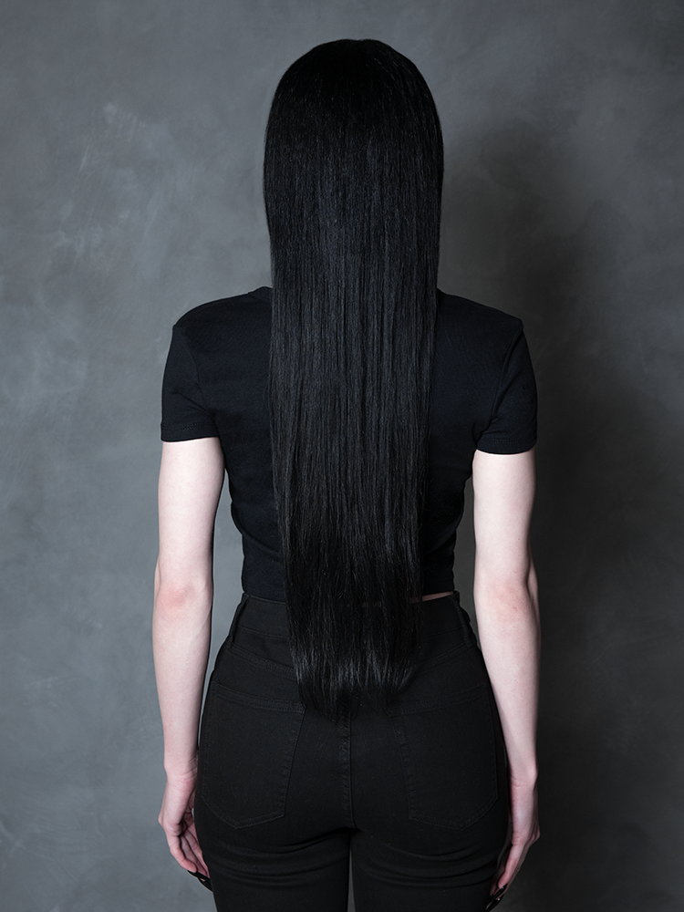 Enveloped in nocturnal mystery, a model styled in dramatic gothic clothing captures the ultimate essence of classic noir horror with a striking, form-flattering black tee.