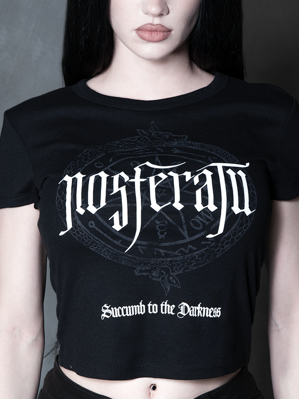 Steeped in romantic melancholy, a model styled in Whimsigoth inspired clothing showcases a sleek, form-fitting black graphic tee that captures the timeless spirit of gothic horror.