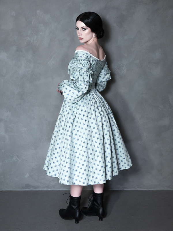 Embodying the alluring depths of dark alternative style, a female model pairs a spellbinding, shadow-kissed botanical dress with an aura of pure cinematic elegance.